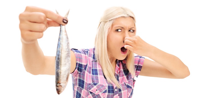 Девушка держит в руках протухшую рыбу
